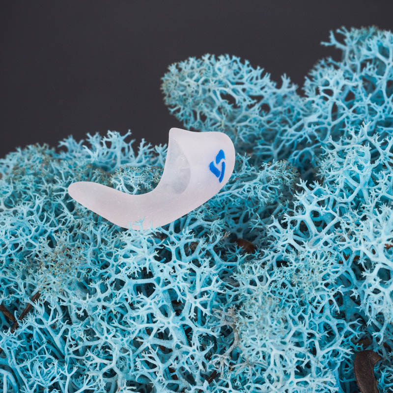 Maßgefertigte CLICK-Otoplastik von myEarmold für Hörsysteme auf blauem 3D-Strukturhintergrund